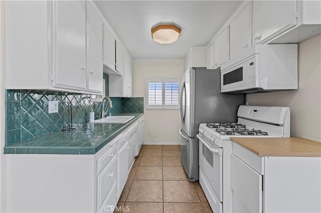 kitchen featuring light tile patterned floors, sink, white appliances, white cabinets, and decorative backsplash