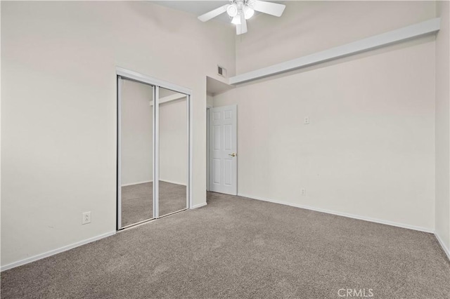 unfurnished bedroom with a high ceiling, carpet, ceiling fan, and a closet