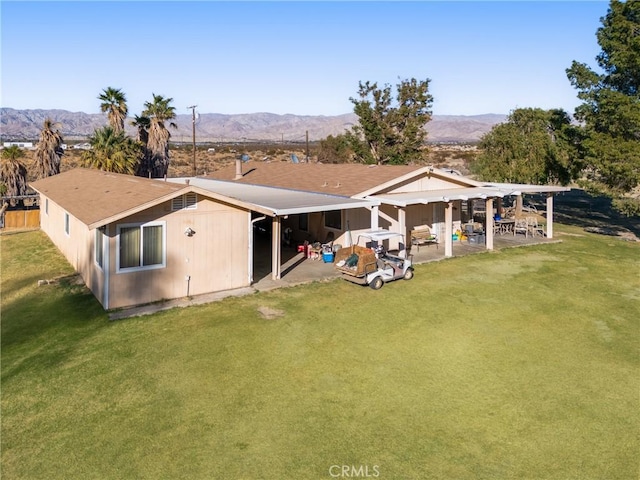 rear view of property with a patio area, a mountain view, and a yard