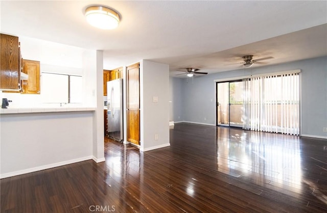 unfurnished living room featuring ceiling fan and dark wood-type flooring