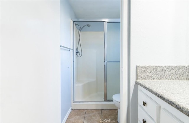 bathroom featuring tile patterned floors, vanity, a shower with shower door, and toilet