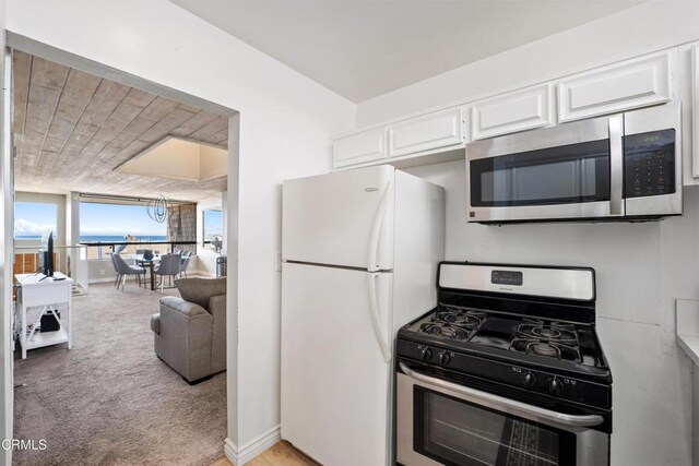 kitchen featuring floor to ceiling windows, white cabinetry, stainless steel appliances, and light carpet