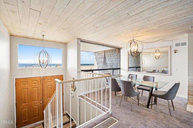 carpeted dining space featuring a water view, an inviting chandelier, and wooden ceiling