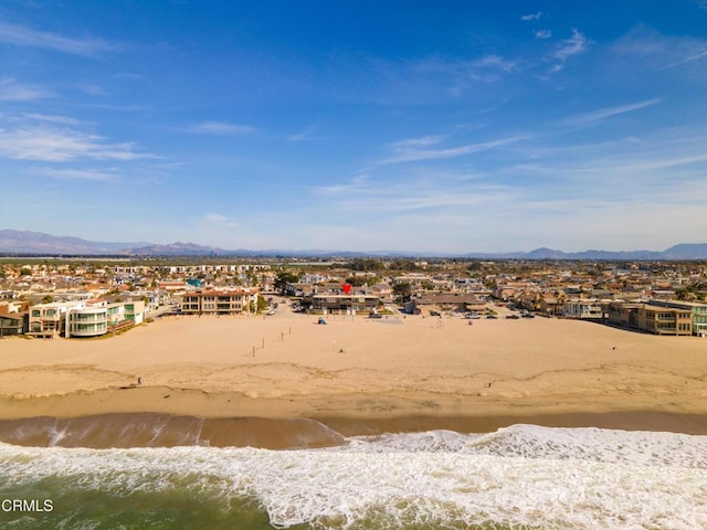 drone / aerial view with a water and mountain view and a view of the beach