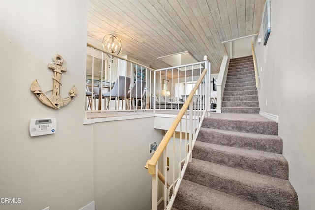 stairs with a chandelier, carpet floors, and wooden ceiling