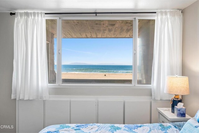 bedroom featuring a water view and a beach view