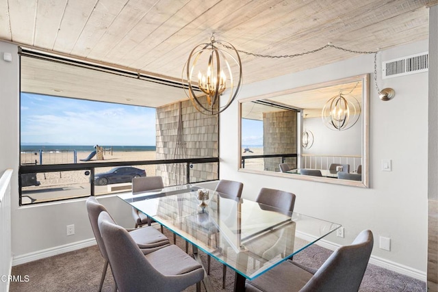 carpeted dining area with a water view, an inviting chandelier, and wooden ceiling