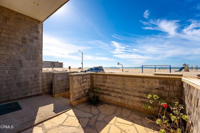 view of patio / terrace featuring a water view and a beach view