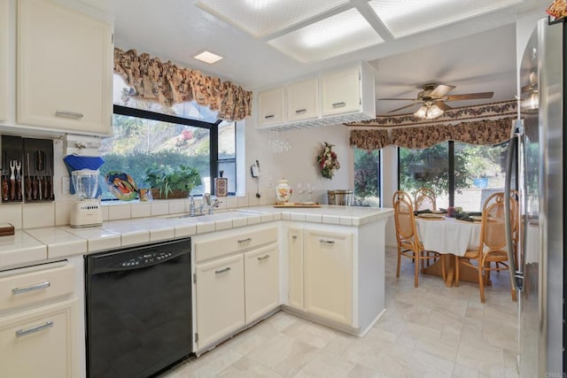 kitchen with tile countertops, dishwasher, sink, ceiling fan, and stainless steel fridge