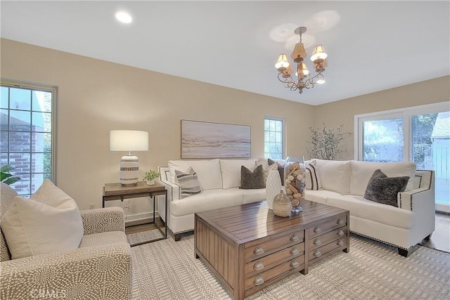 living room with light hardwood / wood-style flooring, plenty of natural light, and a notable chandelier