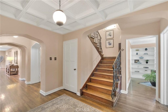 staircase featuring beamed ceiling, hardwood / wood-style floors, and coffered ceiling