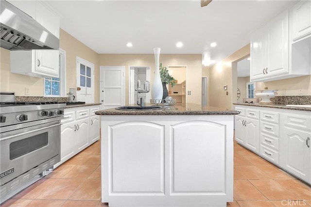 kitchen featuring white cabinetry, a center island, ventilation hood, high end stainless steel range, and light tile patterned flooring