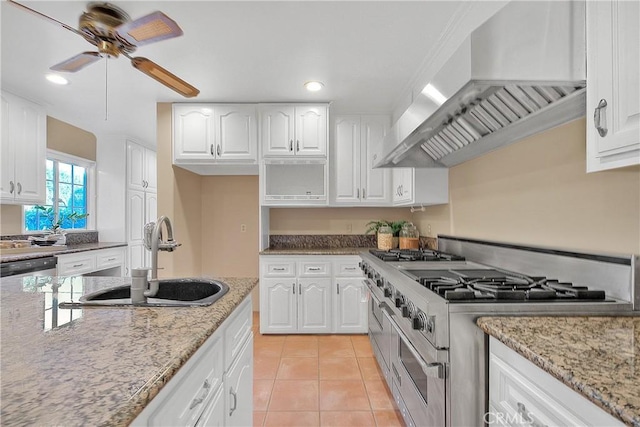 kitchen with sink, stainless steel stove, wall chimney range hood, light tile patterned floors, and white cabinets