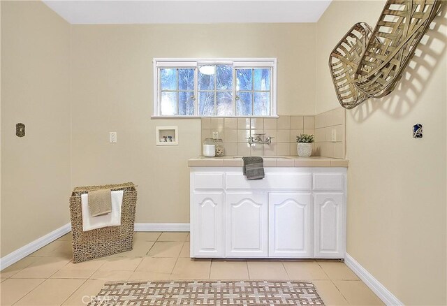 interior space with cabinets, sink, light tile patterned floors, and washer hookup