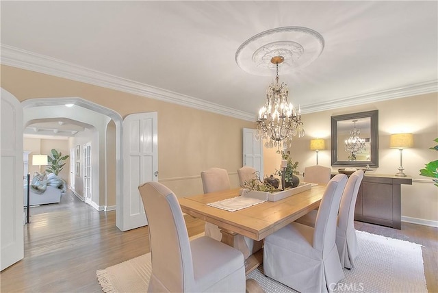 dining area featuring crown molding, a notable chandelier, and hardwood / wood-style flooring