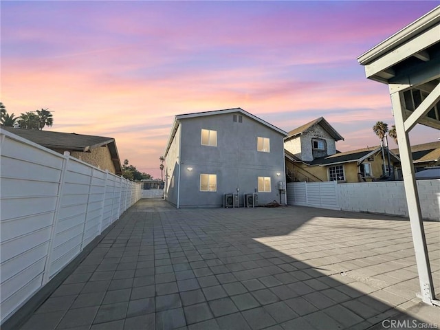 back house at dusk featuring a patio area