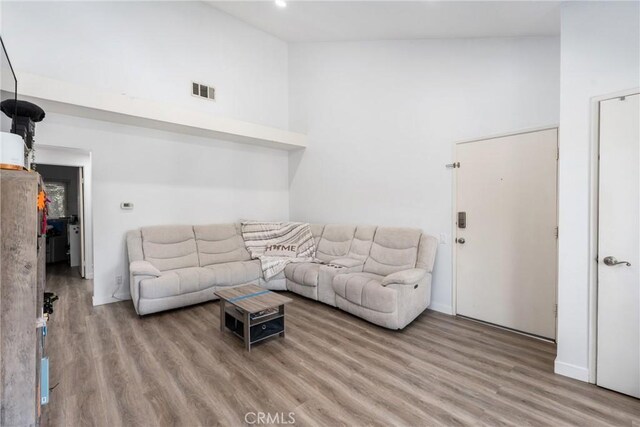 living room with light hardwood / wood-style flooring and high vaulted ceiling