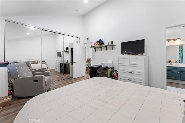 bedroom featuring ensuite bathroom, light hardwood / wood-style flooring, high vaulted ceiling, and a closet