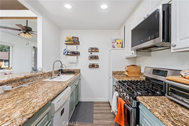 kitchen with white cabinets, sink, dark hardwood / wood-style floors, light stone counters, and stainless steel appliances