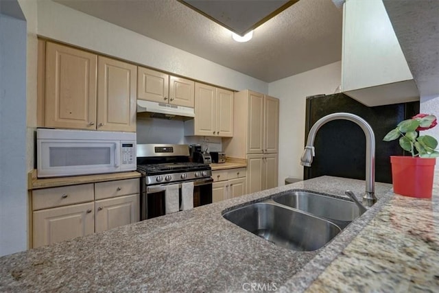 kitchen with white microwave, stainless steel gas range, a textured ceiling, under cabinet range hood, and a sink