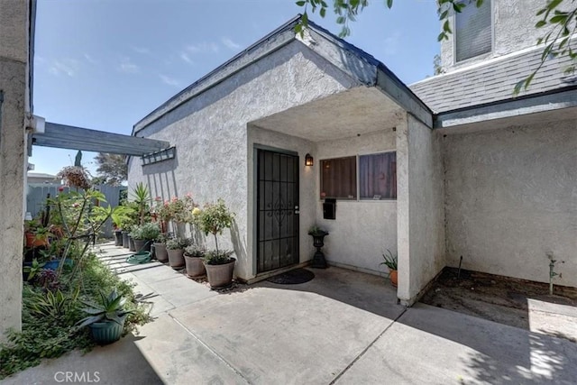 view of exterior entry featuring a patio area and stucco siding