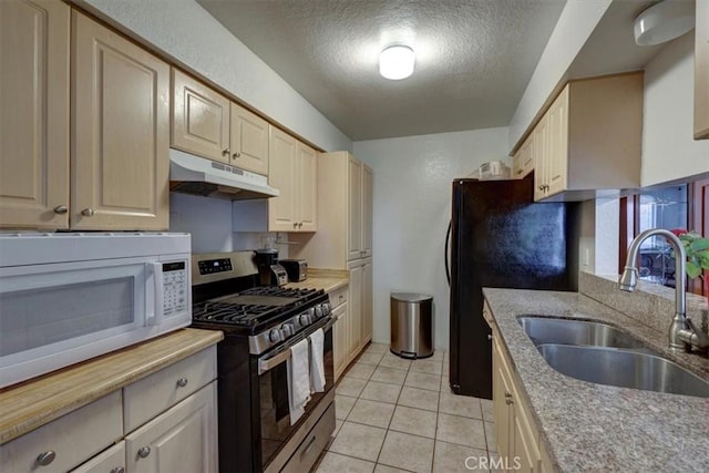 kitchen featuring white microwave, stainless steel range with gas stovetop, light countertops, under cabinet range hood, and a sink