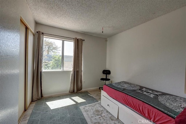 bedroom with a textured ceiling and baseboards