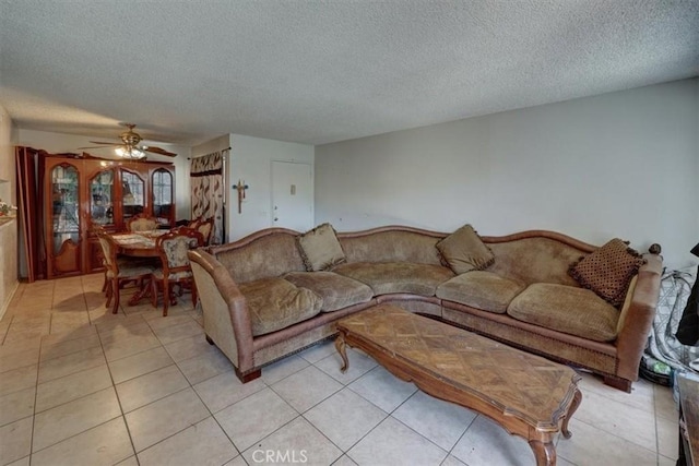 living room with a textured ceiling, light tile patterned flooring, and a ceiling fan