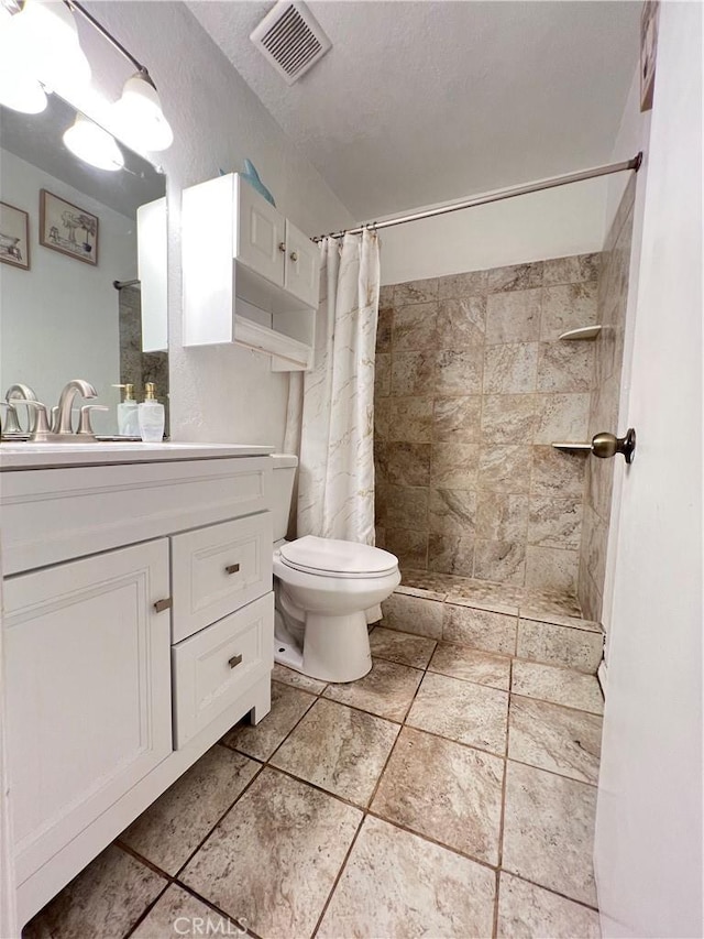 full bath featuring a tile shower, toilet, vanity, and visible vents