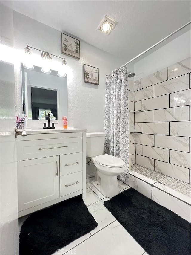 bathroom featuring toilet, visible vents, vanity, marble finish floor, and a shower stall