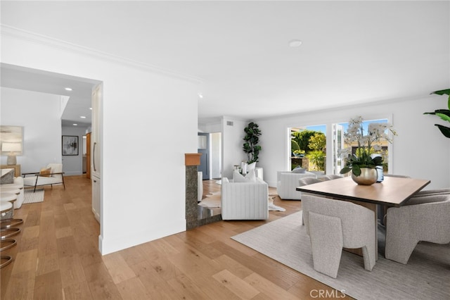 dining area with crown molding and light hardwood / wood-style flooring