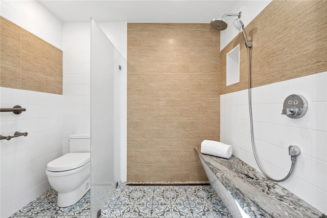 bathroom featuring tile patterned floors, toilet, a shower, and tile walls