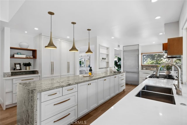 kitchen featuring white cabinetry, hardwood / wood-style floors, hanging light fixtures, and stainless steel built in refrigerator