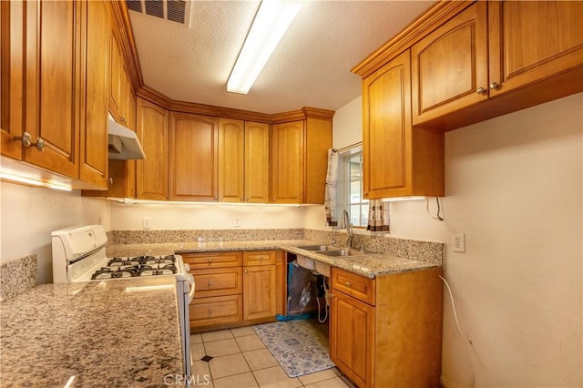 kitchen featuring light stone counters, a textured ceiling, sink, white range with gas stovetop, and light tile patterned flooring