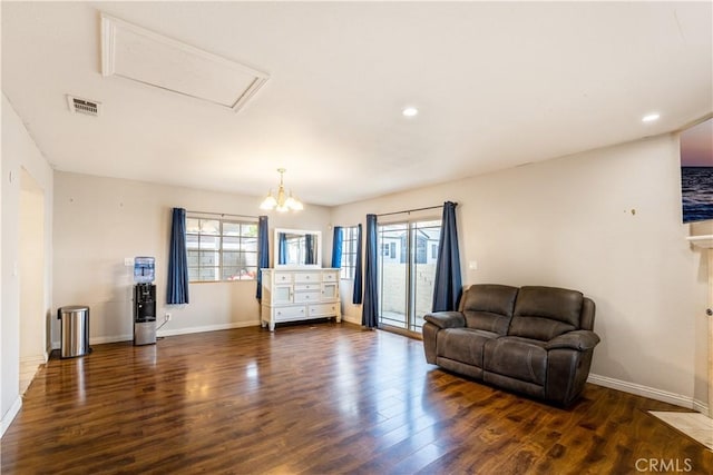 living room with a wealth of natural light, dark hardwood / wood-style flooring, and an inviting chandelier