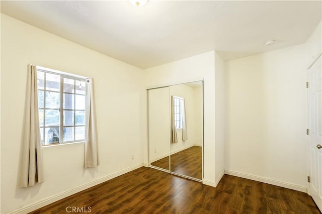 unfurnished bedroom with a closet and dark wood-type flooring