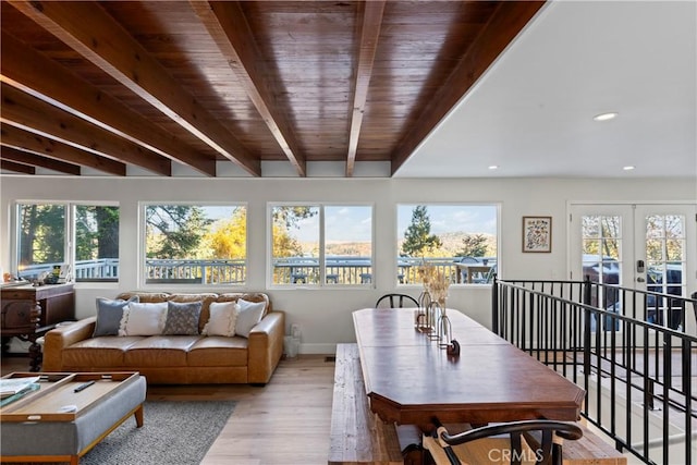 sunroom featuring beamed ceiling, a healthy amount of sunlight, and french doors