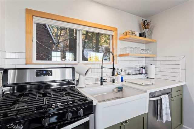 kitchen with appliances with stainless steel finishes, backsplash, green cabinetry, and sink