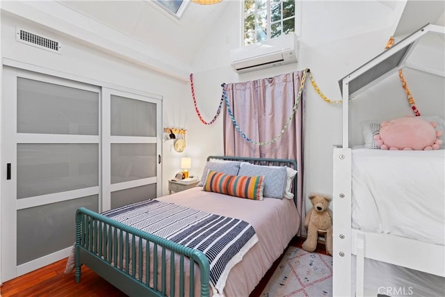 bedroom featuring vaulted ceiling, hardwood / wood-style floors, and a wall mounted air conditioner