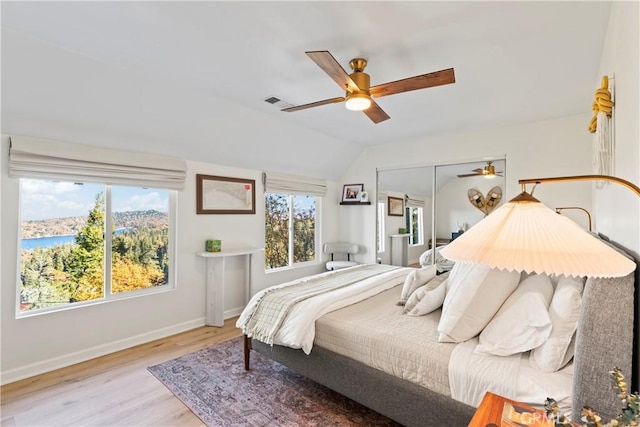 bedroom with multiple windows, ceiling fan, light hardwood / wood-style floors, and vaulted ceiling