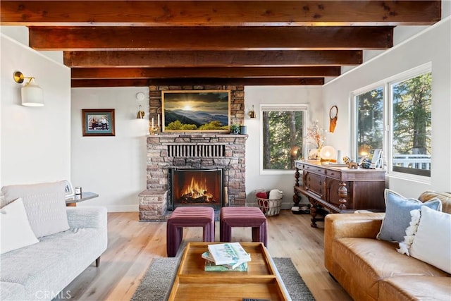 living room with beamed ceiling, a stone fireplace, and light hardwood / wood-style flooring