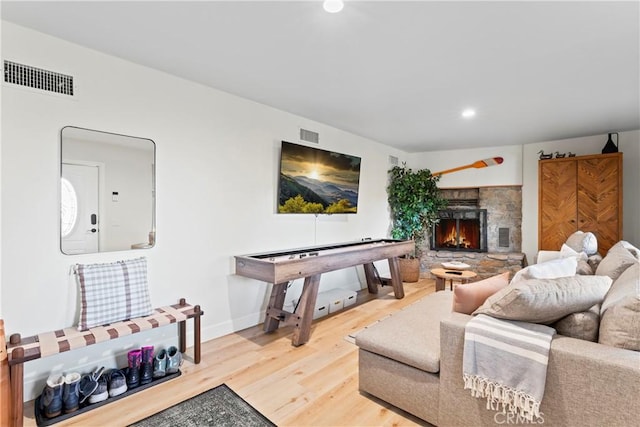 living room featuring a stone fireplace and wood-type flooring