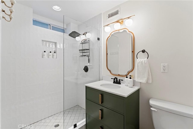 bathroom with vanity, toilet, and tiled shower