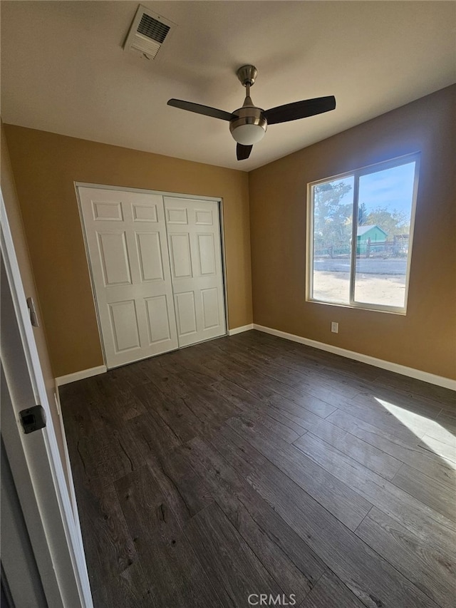 unfurnished bedroom with a closet, dark hardwood / wood-style floors, and ceiling fan