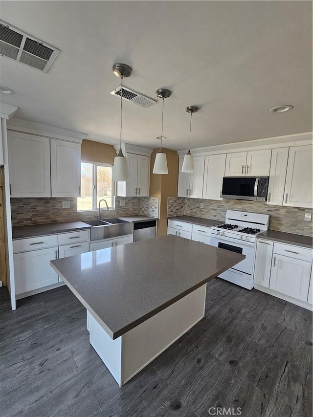 kitchen with a kitchen island, white cabinets, dark wood-type flooring, and appliances with stainless steel finishes