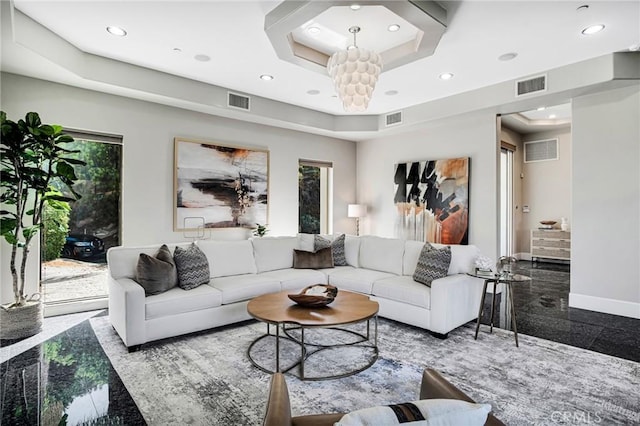 living room featuring a notable chandelier and a tray ceiling