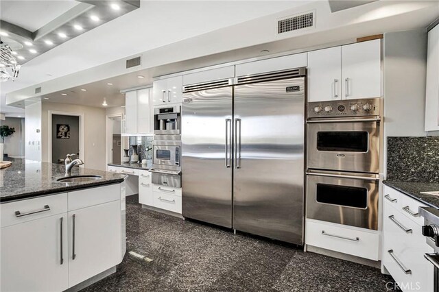 kitchen featuring dark stone countertops, sink, white cabinets, and stainless steel appliances