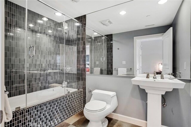 bathroom featuring toilet and bath / shower combo with glass door