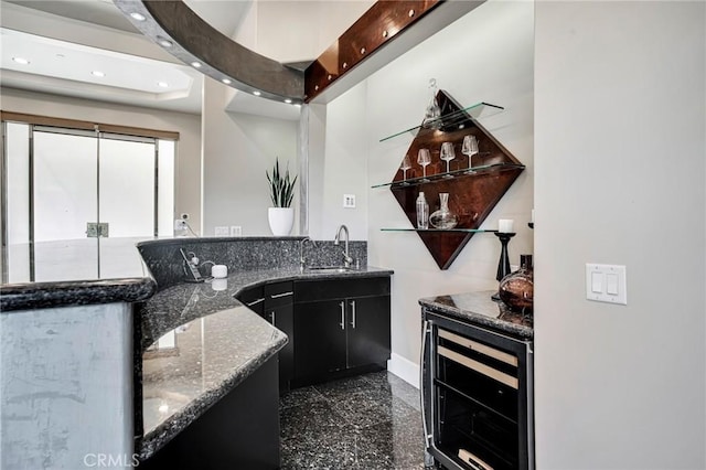 kitchen featuring wine cooler, sink, and dark stone counters