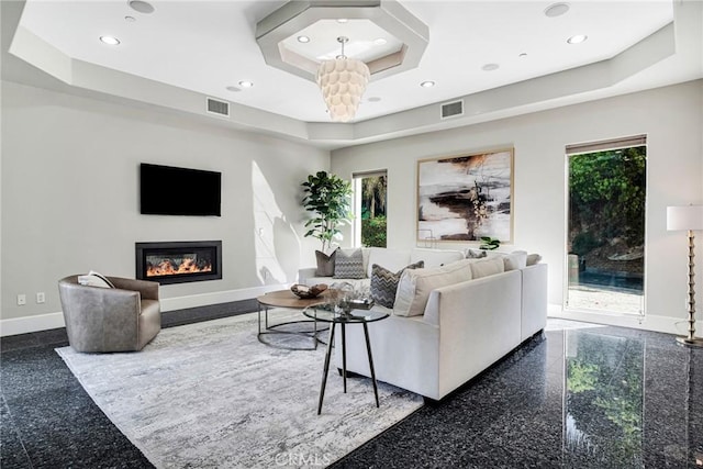 living room featuring a tray ceiling and a notable chandelier